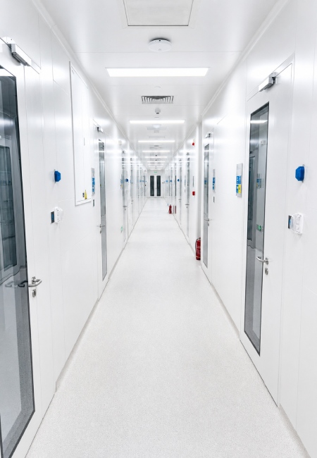 Pharmaceutical cleanroom corridor with smooth white chemical resistant wall panels and flush cleanroom doors